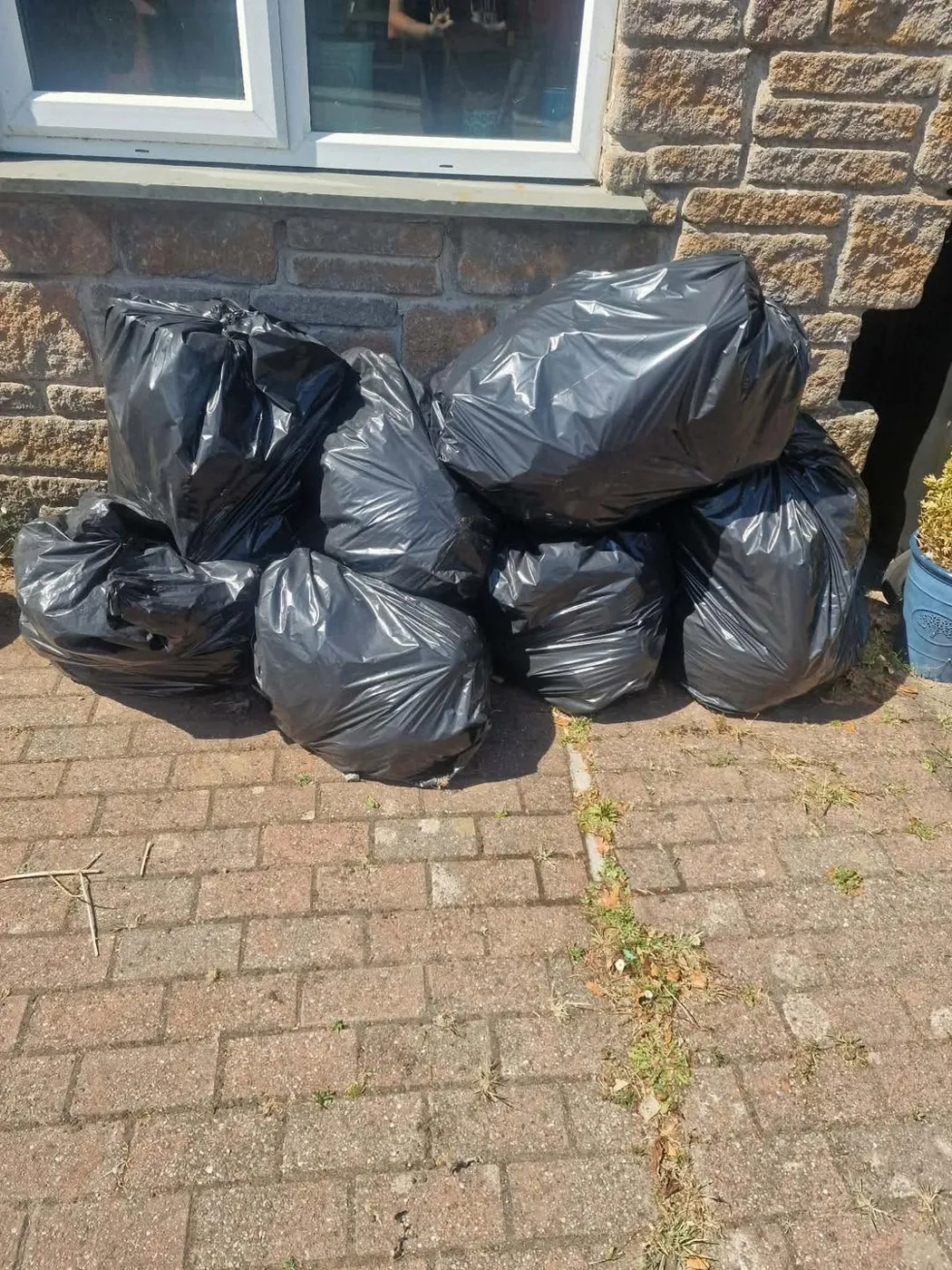 Driveway piled with black rubbish bags before collection